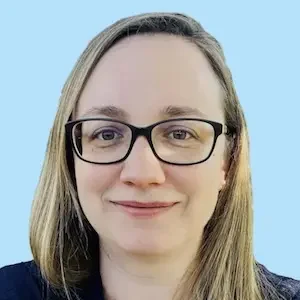 Krankenschwester Frau mit langen hellblonden Haaren, Brille und freundlichem Lächeln.