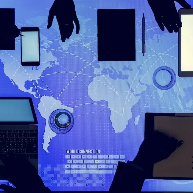Hände nutzen verschiedene elektronische Geräte auf einem globalen Hintergrund.