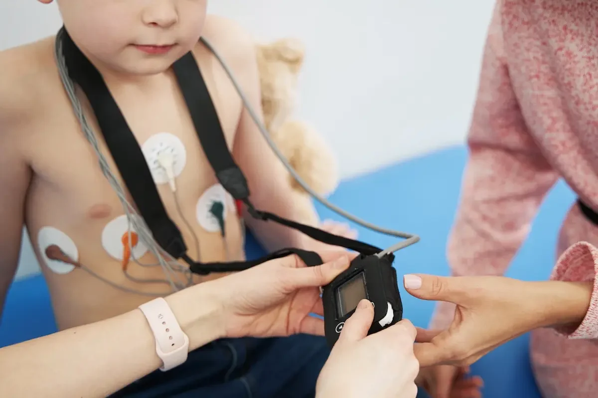 LZ-EKG Untersuchung life in der Kinderherzpraxis Kind bekommt für eine LZ-EKG Untersuchung Elektroden auf die Brust geklebt. Das Gerät hängt über der Schulter