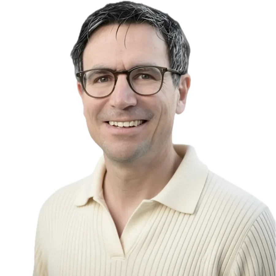 Mann mit Brille und lächelndem Gesicht, trägt ein blaues Polohemd.